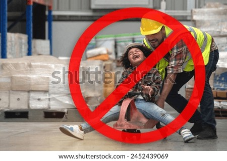 Dangerous, don't play in warehouses, prohibition sign superimposed over the image of African child boy wearing a hard hat and reflective vest playing cart with male worker in warehouse Royalty-Free Stock Photo #2452439069
