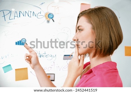 Portrait of young beautiful caucasian businesswoman thinking creative marketing strategy idea in front of whiteboard with mind map and colorful sticky notes. Arm chin. Closeup. Immaculate. Royalty-Free Stock Photo #2452441519