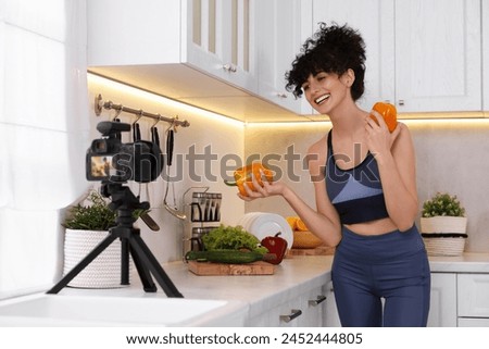 Smiling food blogger explaining something while recording video in kitchen Royalty-Free Stock Photo #2452444805