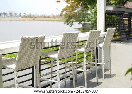 White faux rattan bar chair set. It's furniture that helps add a decorative style to the seating area outside the coffee shop by the lake to make it comfortable and beauty                           