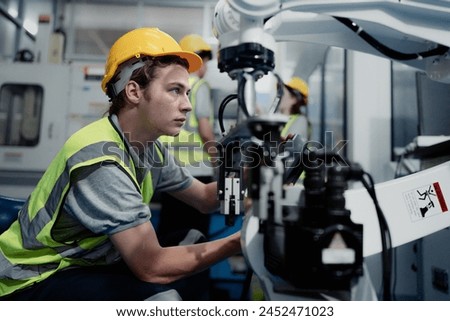 Robotic engineer examining robot arm machine for repairing service. Modern technology technician working on hardware maintenance to fix AI mechanical part of futuristic industrial automated equipment.