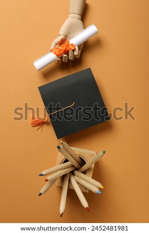 Wooden statuette of a man with a graduation hat and diploma.
