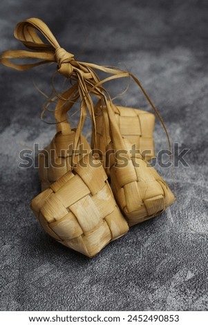 Close up view of Ketupat, Indonesian traditional cuisine very popular during Hari Raya Idul Fitri served on a wooden table. This is made of the white rice, usually served with opor ayam on Ied day. Royalty-Free Stock Photo #2452490853