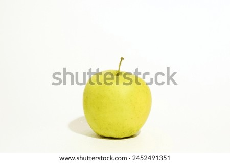 A fresh green apple rests elegantly on top of a clean white table