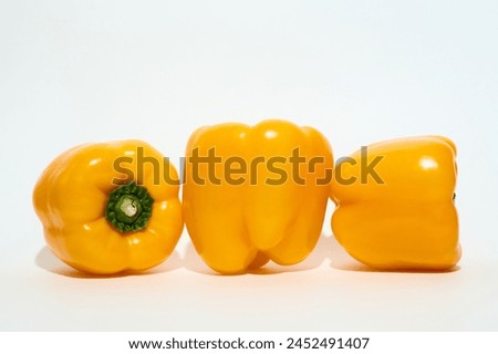 A group of vibrant yellow peppers are neatly stacked on top of each other, creating a visually appealing arrangement. The peppers vary in size and shape, with their glossy skin reflecting light.