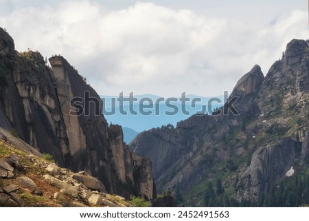 Deep canyon with sharp rocks. Awesome scenic view to great mountains in distance behind deep gorge. Wonderful mountain landscape with giant rockies and deep abyss. Perfect summer image for wall Royalty-Free Stock Photo #2452491563