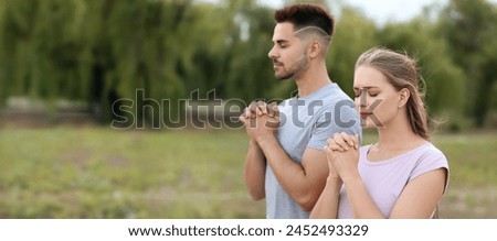 Religious young couple praying outdoors. Banner for design
