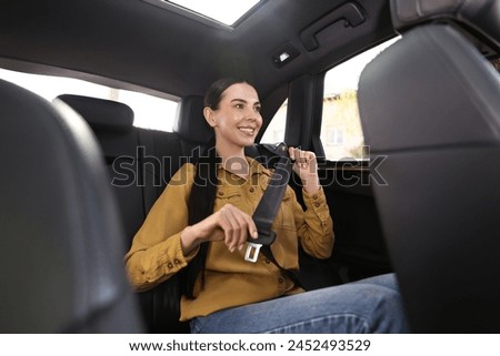 Woman fastening safety seat belt inside modern car Royalty-Free Stock Photo #2452493529
