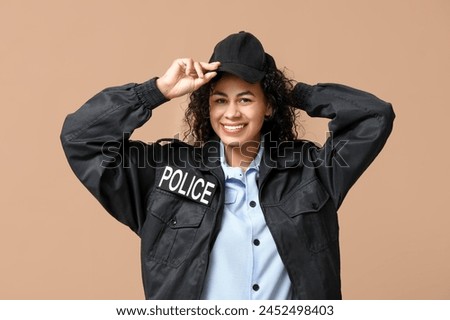 Beautiful young happy African-American policewoman on brown background Royalty-Free Stock Photo #2452498403