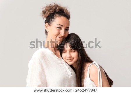 Beautiful mature woman with her teenage daughter on grey background. Mother's day