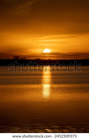 The sky and the lake are red-tinged during sunset, a beautiful sunset on the lake in early spring Royalty-Free Stock Photo #2452509373