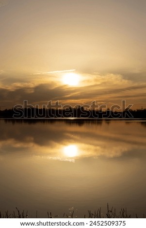 The sky and the lake are red-tinged during sunset, a beautiful sunset on the lake in early spring Royalty-Free Stock Photo #2452509375