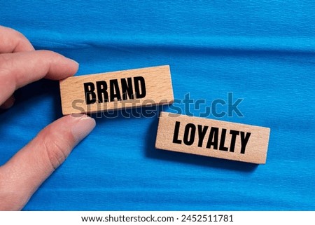 Brand loyalty words written on wooden blocks with blue background. Conceptual brand loyalty symbol. Copy space.