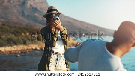 Couple, photography and beach with camera for trip, memory or outdoor moment together in nature. Woman or photographer taking picture of man, boyfriend or partner on adventure by ocean coast