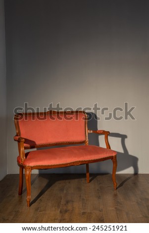 Vintage. Classic red elegant couch standing against grey wall