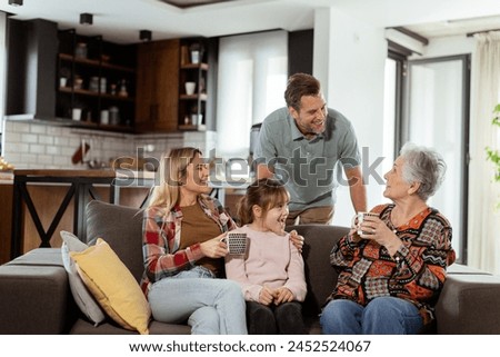 Heartwarming scene unfolds as a multi-generational family gathers on a couch to present a birthday cake to a delighted grandmother, creating memories to cherish Royalty-Free Stock Photo #2452524067