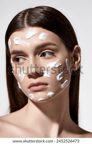 A young woman exudes beauty with a white cream on her face, enhancing her features.