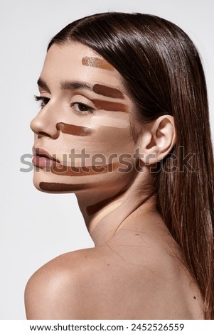 Attractive young woman adorned with layers of foundation, showcasing intricate makeup artistry. Royalty-Free Stock Photo #2452526559