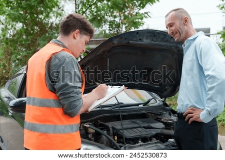 Insurance agent personnel wear orange reflective safety suits. Talking with the car owner Assessing car damage after a car crash Preparing insurance claim documents for a Caucasian man to sign.