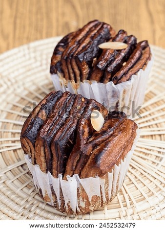 a photography of two cupcakes with chocolate and nuts on a plate.