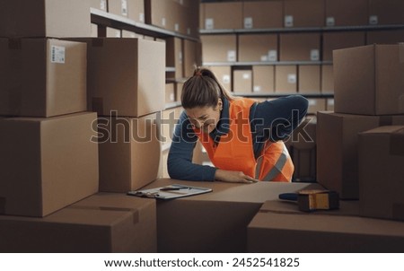 Female warehouse worker touching her lower back, she is having back pain Royalty-Free Stock Photo #2452541825