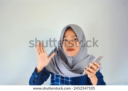 Portrait of an Asian woman with a happy gesture playing with a smartphone in her hand