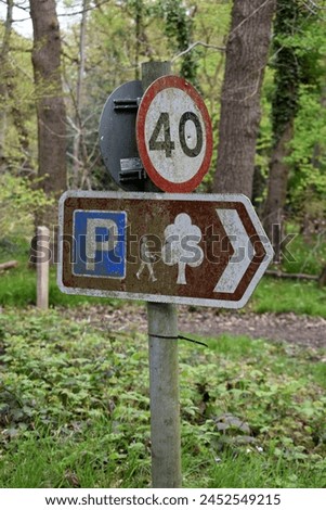 A double-sided 40 mph speed sign and a woodland walking and parking sign fixed to a galvanized post against a woodland background 
