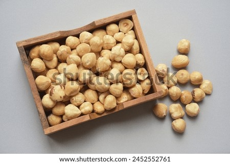 Close up photograph of roasted hazelnuts in wooden rectangular bowl Wholefood Top view Royalty-Free Stock Photo #2452552761