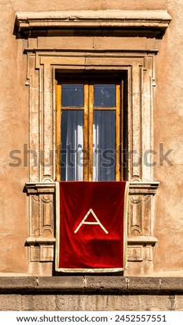 window with red banner or pennant with letter A for decotarion of old building facade for celebration of Saint Agata day in Catania