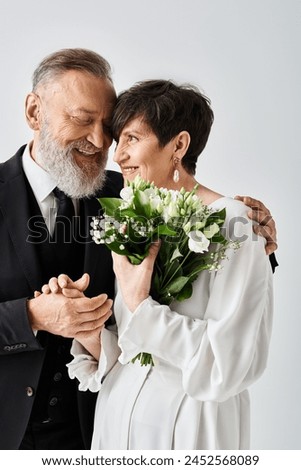 A middle aged bride and groom in wedding gowns are standing side by side, celebrating their special day in a studio setting. Royalty-Free Stock Photo #2452568089