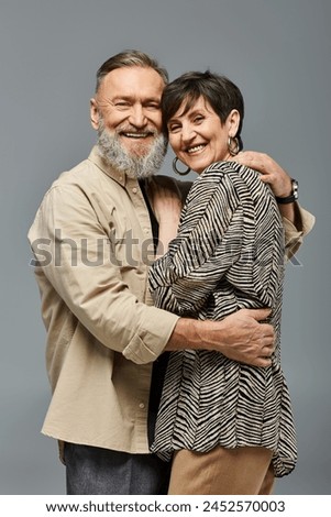 A middle aged couple in stylish attire sharing a warm, heartfelt hug in a studio setting, showing love and connection. Royalty-Free Stock Photo #2452570003