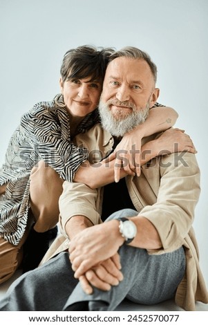 A middle-aged couple in stylish attire share a heartfelt hug, expressing love and connection in a studio setting. Royalty-Free Stock Photo #2452570077