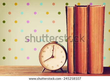 stack of old books, clock over wooden table