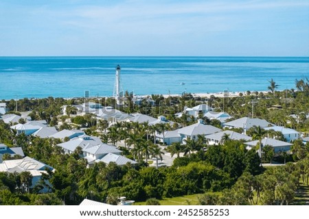 Rich neighborhood with expensive vacation homes and white lighthouse on ocean shore in Boca Grande, small town on Gasparilla Island in southwest Florida. Wealthy waterfront residential area. Royalty-Free Stock Photo #2452585253
