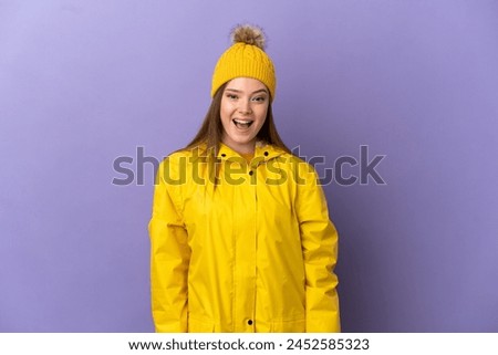 Teenager girl wearing a rainproof coat over isolated purple background with surprise facial expression