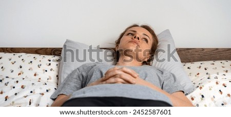 Tired overworked depressed frustrated woman lying down on the bed and looking up with blank expression. Mental illness and hopelessness. Royalty-Free Stock Photo #2452587601