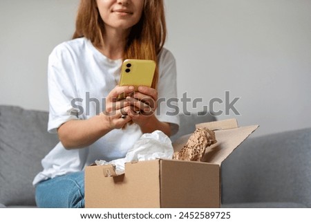 E-commerce and online stores. Express delivery service and online service rating. Woman unpacking cardboard and taking picture of purchase.