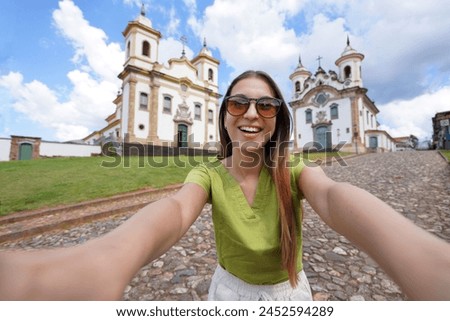 Holidays in Minas Gerais, Brazil. Beautiful traveler girl takes selfie picture with smartphone in Mariana, Minas Gerais, Brazil.