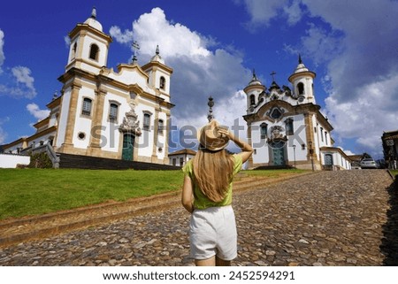 Holidays in Minas Gerais, Brazil. Back view of traveler girl visiting historical town of Mariana with baroque colonial architecture. Mariana is the oldest city in the state of Minas Gerais, Brazil. Royalty-Free Stock Photo #2452594291