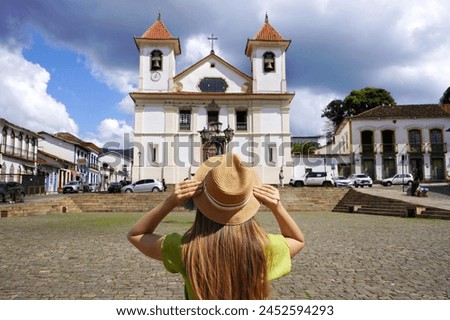 Tourism in Mariana, Brazil. Back view of young tourist woman in Mariana Cathedral square in Minas Gerais, Brazil. Royalty-Free Stock Photo #2452594293