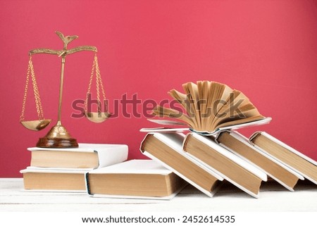 Law concept - Open law book, Judge's gavel, scales, Themis statue on table in a courtroom or law enforcement office. Wooden table, red background.