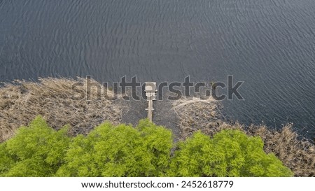 Shore of a forest lake. Fishing pier on the lake. Aerial drone view.