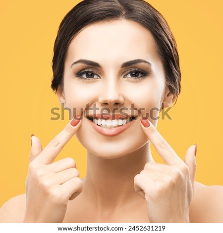 Happy excited woman pointing toothy smile. Face portrait of optimistic girl, isolated against yellow background. Optimism or Dental Health Care concept. Square composition image. Royalty-Free Stock Photo #2452631219