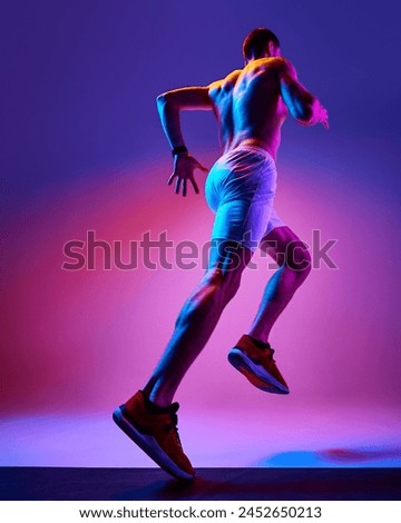 Bottom view of muscular, athletic young man training shirtless, running on gradient pink purple background in neon light. Concept of active and healthy lifestyle, sport, hobby, motivation, endurance