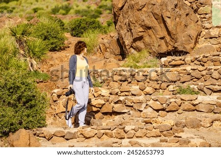 Tourist woman walking with camera, take travel picture outdoors on mediterranean nature in Spain.