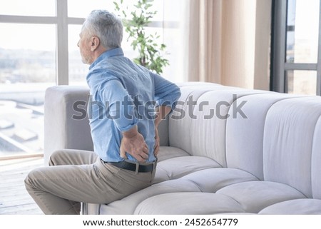 Senior caucasian old elderly man suffering from back pain at home. Rheumatism, ache, health problems. Sedentary lifestyle. People, healthcare and problem concept Royalty-Free Stock Photo #2452654779