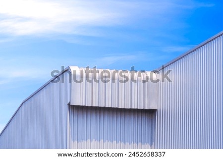 Geometric metal industrial factory building with aluminium roof eave against blue sky background, perspective side view with copy space 