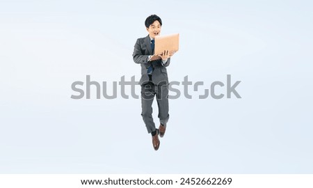 Full body photo of a male business person jumping while looking at a laptop