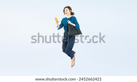 Full body photo of a Caucasian woman jumping while looking at her smartphone