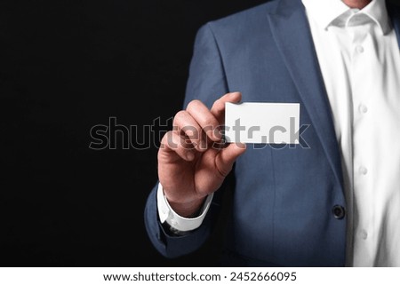 Businessman holding blank business card on black background, closeup. Space for text